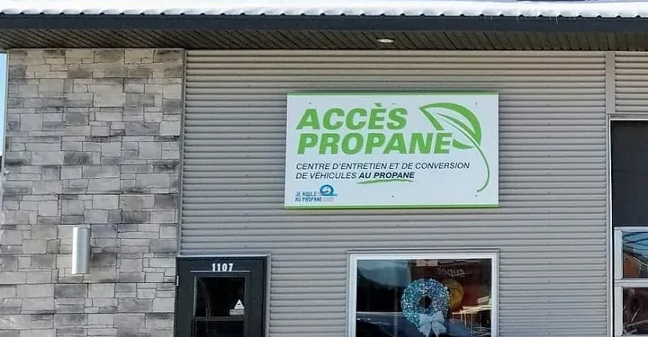 Affiche « Accès Propane — centre d’entretien et de conversion de véhicules au propane » posée sur le mur de l’atelier, à côté de la porte numéro 1107.